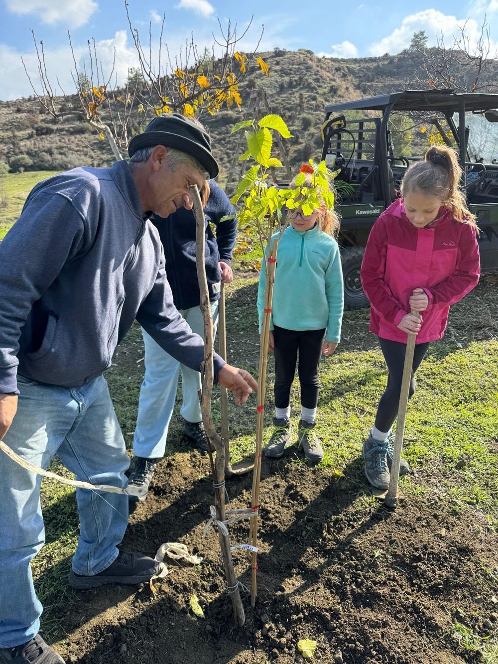 Sofroni planting a young tree on the Kampia estate with two of the family's children